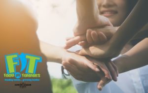 Women's hands stack in a gesture of teamwork. Food in Tummies logo attached.